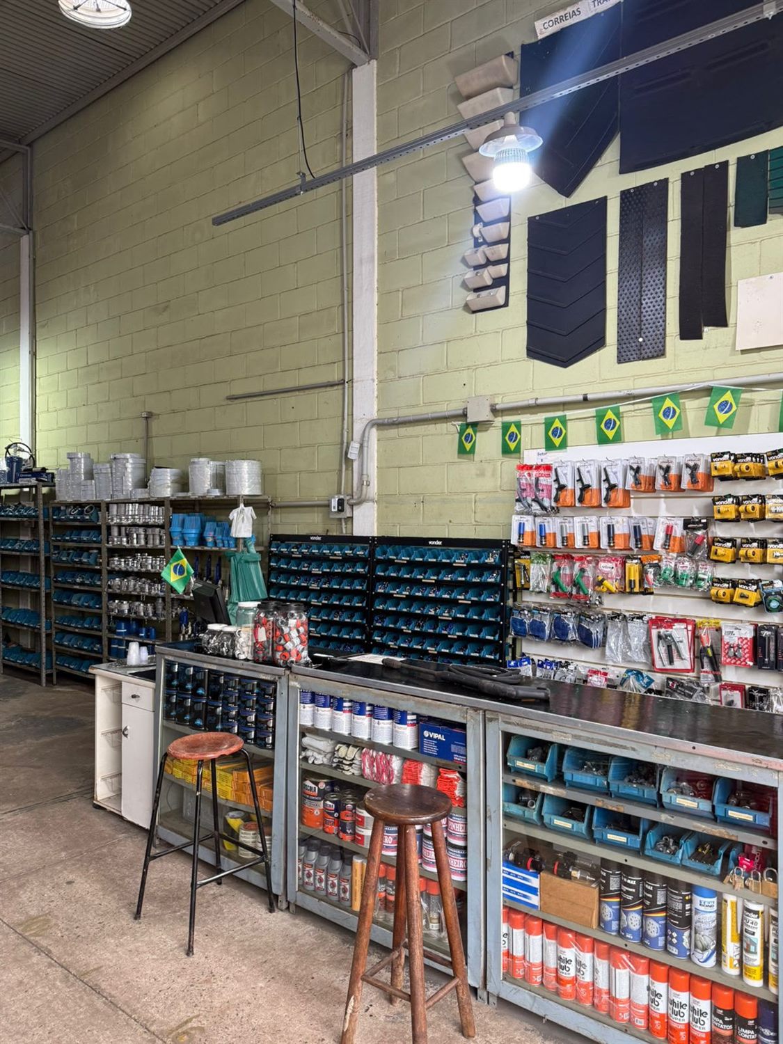 Interior da loja Comang, com prateleiras de conexões, ferramentas e amostras de correia